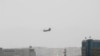 Un helicóptero Chinook de Estados Unidos vuela cerca de la Embajada de Estados Unidos, a la izquierda, en Kabul, Afganistán, el domingo 15 de agosto de 2021.