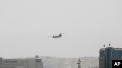 Un helicóptero Chinook de Estados Unidos vuela cerca de la Embajada de Estados Unidos, a la izquierda, en Kabul, Afganistán, el domingo 15 de agosto de 2021.