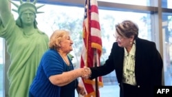 Un nuevo ciudadano estadounidense Tamam Shanazarian, a la izquierda, le da la mano a Nancy Alby, directora de campo de USCIS Los Ángeles, durante una ceremonia de naturalización antes del Día Mundial del Refugiado realizada por los Servicios de Ciudadanía
