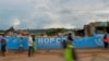 FILE - People walk across a bridge with a message written on the barriers advocating personal efforts to stem the spread of the COVID-19 coronavirus in the Kibera slum, Nairobi, on April 14, 2020. 