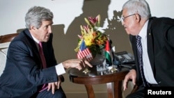 U.S. Secretary of State John Kerry (L) and Palestinian President Mahmoud Abbas talk at a meeting at the presidential compound in the West Bank city of Ramallah, Jan. 4, 2014. 