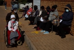 FILE - An elderly woman leaves as others wait to receive the Pfizer COVID-19 vaccine, at a clinic at Orange Farm, near Johannesburg, June 3, 2021.