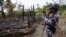 FILE - A Myanmar border guard police officer takes pictures at the remains of a burned house in Tin May village, northern Rakhine state, Myanmar.
