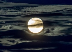 FILE - The full moon shines surrounded by clouds in the outskirts of Frankfurt, Germany, Sept. 2, 2020.