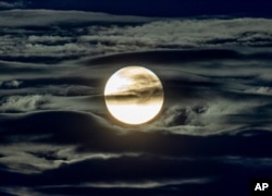 FILE - The full moon shines surrounded by clouds in the outskirts of Frankfurt, Germany, Sept. 2, 2020.