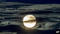 FILE - The full moon shines surrounded by clouds in the outskirts of Frankfurt, Germany, Sept. 2, 2020.
