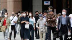 People wearing face masks to protect against the spread of the coronavirus walk on a crossing in Tokyo, Japan, Aug. 16, 2021.