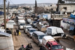 FILE - Civilians flee from Idlib toward the north to find safety inside Syria near the border with Turkey, Feb. 15, 2020.