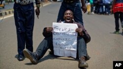 An opposition protester holds a placard denouncing electoral commission officials, at a demonstration in downtown Nairobi, Kenya, Sept. 26, 2017. 