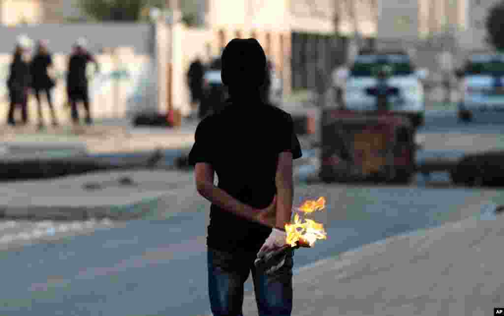 An anti-government protester prepares to throw a gasoline bomb at riot police during clashes in Malkiya village, Bahrain, January 7, 2013.