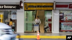 A security guard stands at the door where hostages walked out on Monday at the V-Mall in Manila, Philippines, March 3, 2020. 