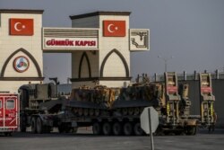 A Turkish forces truck transporting armored personnel carriers, crosses the border with Syria in Karkamis, Gaziantep province, southeastern Turkey, Oct. 15, 2019.