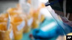 A health worker takes a sample for a PCR test for the COVID-19 coronavirus at a hospital in Coslada, Spain, Monday, April 20, 2020. 