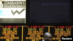 FILE: A Zimbabwe Stock Exchange official walks past an electronic display screen showing an 11-percent drop at the close of trading, in Harare, Zimbabwe, August 5, 2013.