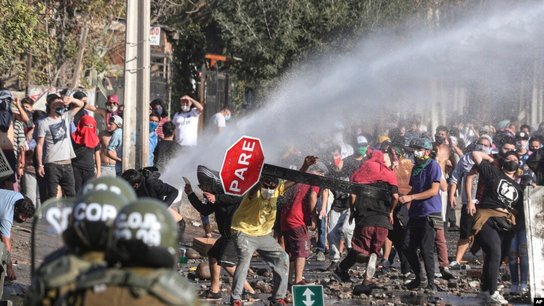 Demonstrators, some wearing protective face masks amid the new coronavirus pandemic, clash with the police during a protest demanding food aid from the government, at a poor neighborhood in Santiago, Chile, May 18, 2020.