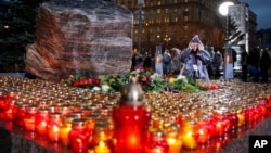 People gather at a monument with candles outside the former KGB headquarters in Moscow, Russia, Oct. 29, 2019, in an annual commemoration of the victims of purges under Soviet dictator Joseph Stalin.