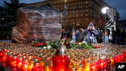 People gather at a monument with candles outside the former KGB headquarters in Moscow, Russia, Oct. 29, 2019, in an annual commemoration of the victims of purges under Soviet dictator Joseph Stalin.