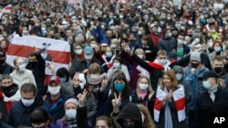 People with old Belarusian national flags march during an opposition rally to protest the official presidential election results in Minsk, Belarus, Oct. 25, 2020. 