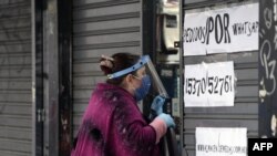 Una mujer que usa una máscara facial, quita la orden de cierre en una tienda parcialmente cerrada durante el confinamiento impuesto por el gobierno contra la propagación del nuevo coronavirus en Buenos Aires, Argentina, el 22 de mayo de 2020.