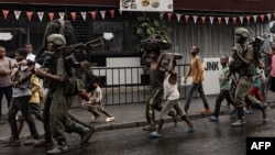 Members of the M23 armed group walk alongside residents through a street of the Keshero neighborhood in Goma, on January 27, 2025.