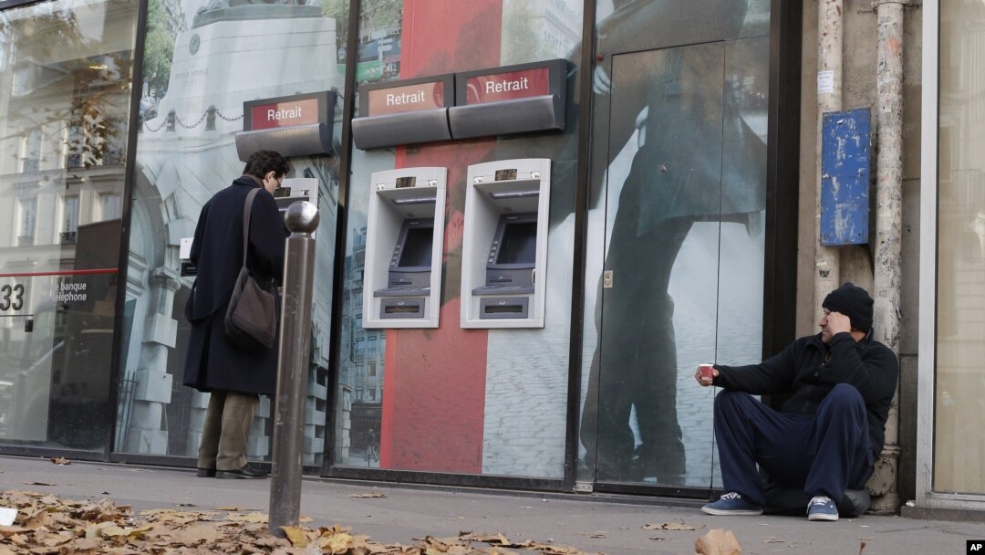 Một người vô gia cư ngồi trước cửa một ngân hàng ở Paris. 