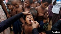 Seorang anak pengungsi Rohingya sedang menerima vaksinasi oral kolera yang dibagikan oleh Organisasi Kesehatan Dunia (WHO) dengan bantuan relawan dan LSM setempat, di Cox's Bazar, Bangladesh, 11 Oktober 2017. (Foto: Reuters)