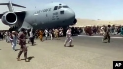 Stotine ljudi trči duž piste pored američkog vojnog transportnog aviona C-17, dok se on kreće na Međunarodnom aerodromu "Hamid Karzai" u Kabulu 16. avgusta 2021. (Foto: AP)