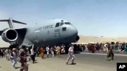 Ratusan orang berlarian di sisi pesawat Air Force C-17 milik AS saat bergerak di landasan pacu bandara internasional, di Kabul, Afghanistan, 16 Agustus. 2021.