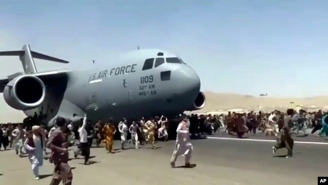 Ratusan orang berlarian di sisi pesawat Air Force C-17 milik AS saat bergerak di landasan pacu bandara internasional, di Kabul, Afghanistan, 16 Agustus. 2021.
