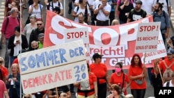 FILE - People hold placards and banners during a demonstration called by far-right and COVID-19 deniers to protest restrictions related to the coronavirus pandemic, in Berlin, Aug. 29, 2020.