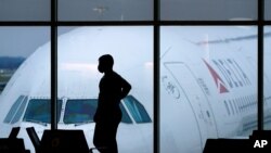资料照片：在哈茨菲尔德-杰克逊亚特兰大国际机场，一名乘客戴着口罩等候登上一架达美航空公司的班机。 (2021年2月18日)