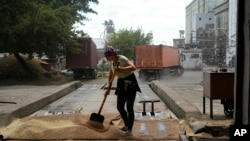 ARCHIVO - Una trabajadora barre grano luego de ser descargado por camiones en un elevador, en Melitopol, en el sur de Ucrania, el 14 de julio de 2022.
