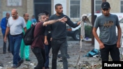 People inspect the area of Ahli Arab hospital, where hundreds of Palestinians were killed in a blast that Israeli and Palestinian officials blamed on each other, and where Palestinians who fled their homes were sheltering amid the ongoing conflict, in Gaza City, Oct. 18, 2023.