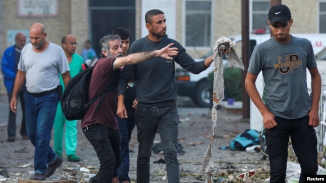 People inspect the area of Ahli Arab hospital, where hundreds of Palestinians were killed in a blast that Israeli and Palestinian officials blamed on each other, and where Palestinians who fled their homes were sheltering amid the ongoing conflict, in Gaza City, Oct. 18, 2023.