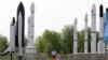 FILE - A woman walks with a child as they visit a park displaying replicas of foreign and domestic space vehicles in Beijing, China, June 26, 2016. China and the United States announced a new round of talks with China about civil space exploration.