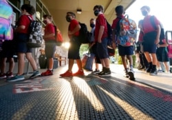 Elementary school students line up to enter school for the first day of classes in Richardson, Texas, Aug. 17, 2021.