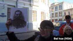 导游帕维尔手举的照片是其中的一名行刑队长,名叫马格，他兼秘密警察后勤大楼的司令。马格仅有2年级文化，后来因为酗酒和酒精中毒死去。帕维尔左侧就是卢毕扬卡11号的秘密警察后勤大楼。(美国之音白桦拍摄)