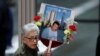 Seorang perempuan membawa foto Wilder Gomez, seorang bartender di restoran Windows on the World di lantai 103 di World Trade Center, dalam upacara peringatan 17 tahun serangan teror terhadap Amerika Serikat, 11 September 2018 di New York.