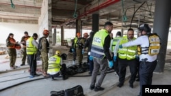 نیروهای امدادی بر صحنه اصابت موشک در شهر یهود که به کشته شدن دو کارگر خارجی منجر شد