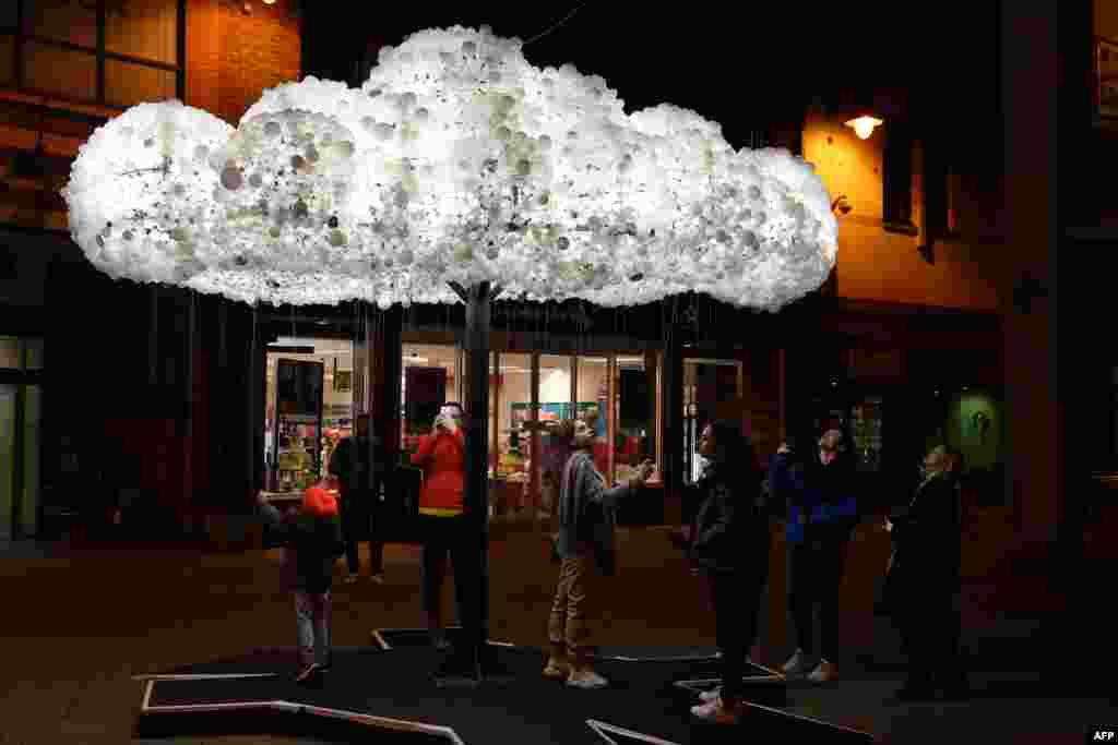 Visitors admire the artwork &#39;Cloud&#39;, formed from 6,000 incandescent light bulbs, during a rehearsal for &#39;Lumiere Durham&#39; light festival in Durham, northeast England, Nov. 13, 2019.