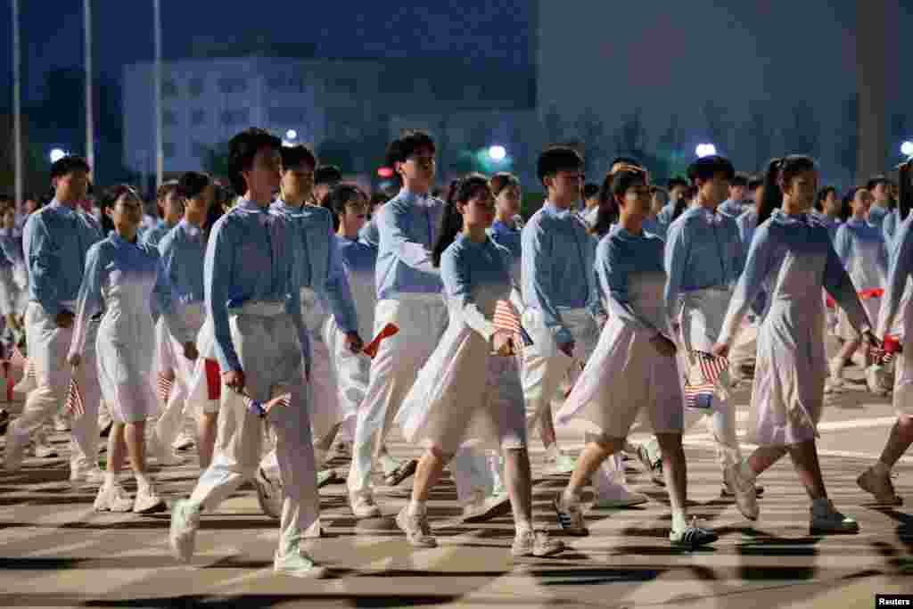 中国青年在北京首都国际机场手持美中小国旗，准备欢迎乘“空军一号”专机抵达的美国总统特朗普。(2026年5月13日)
