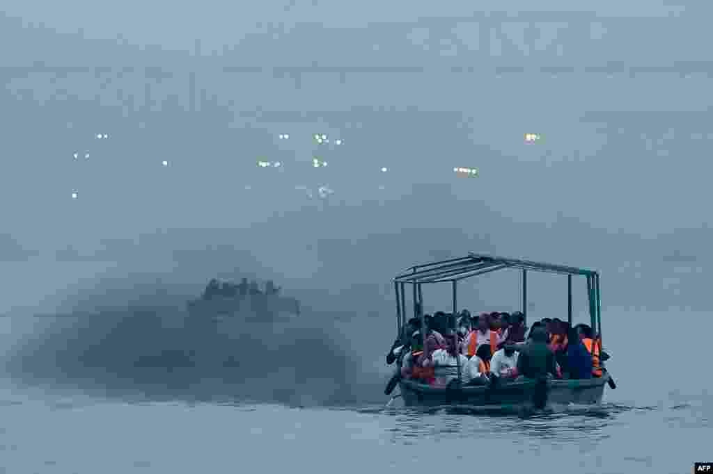 People ride a motor boat across river Ganges in Varanasi, India. (Photo by Niharika KULKARNI / AFP)