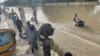 Residents leave the flooded areas with their belongings in Maiduguri, northern Borno state, Nigeria, Sept. 15, 2024.