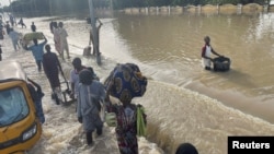 Residents leave the flooded areas with their belongings in Maiduguri, northern Borno state, Nigeria, Sept. 15, 2024.