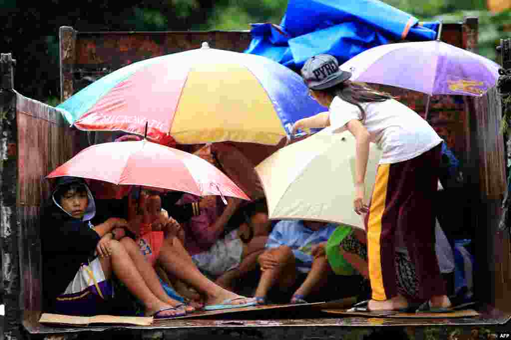 Residents sit in a truck after the local government implemented preemptive evacuations at Barangay Matnog, Daraga, Albay province, the Philippines, due to the approaching typhoon Nock-Ten.