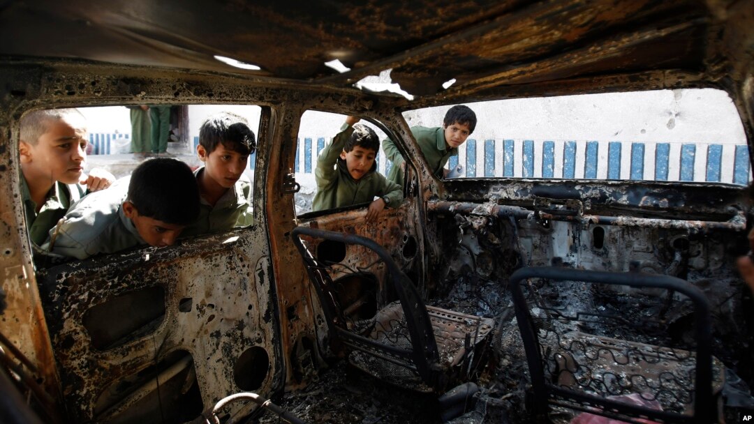 FILE - Yemeni boys look at a vehicle destroyed during a police raid on an al-Qaida militant hideout in the Arhab region, north of Sana'a, Yemen, May 27, 2014.