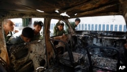 FILE - Yemeni boys look at a vehicle destroyed during a police raid on an al-Qaida militant hideout in the Arhab region, north of Sana'a, Yemen, May 27, 2014.