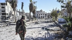 A member of the Syrian Democratic Forces (SDF) walks through a heavily damaged street leading to an Armenian church in Raqqa, Syria, Oct. 18, 2017.