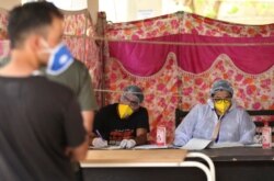 An Indian doctor interacts with a man as another waits for his turn at a COVID-19 screening facility inside a government-run hospital in Jammu, June 27, 2020.