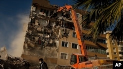 Un trabajador pasa frente a un edificio dañado por el sismo del 30 de octubre que obreros están demoliendo. Esmirna, Turquía, 4 de noviembre de 2020.